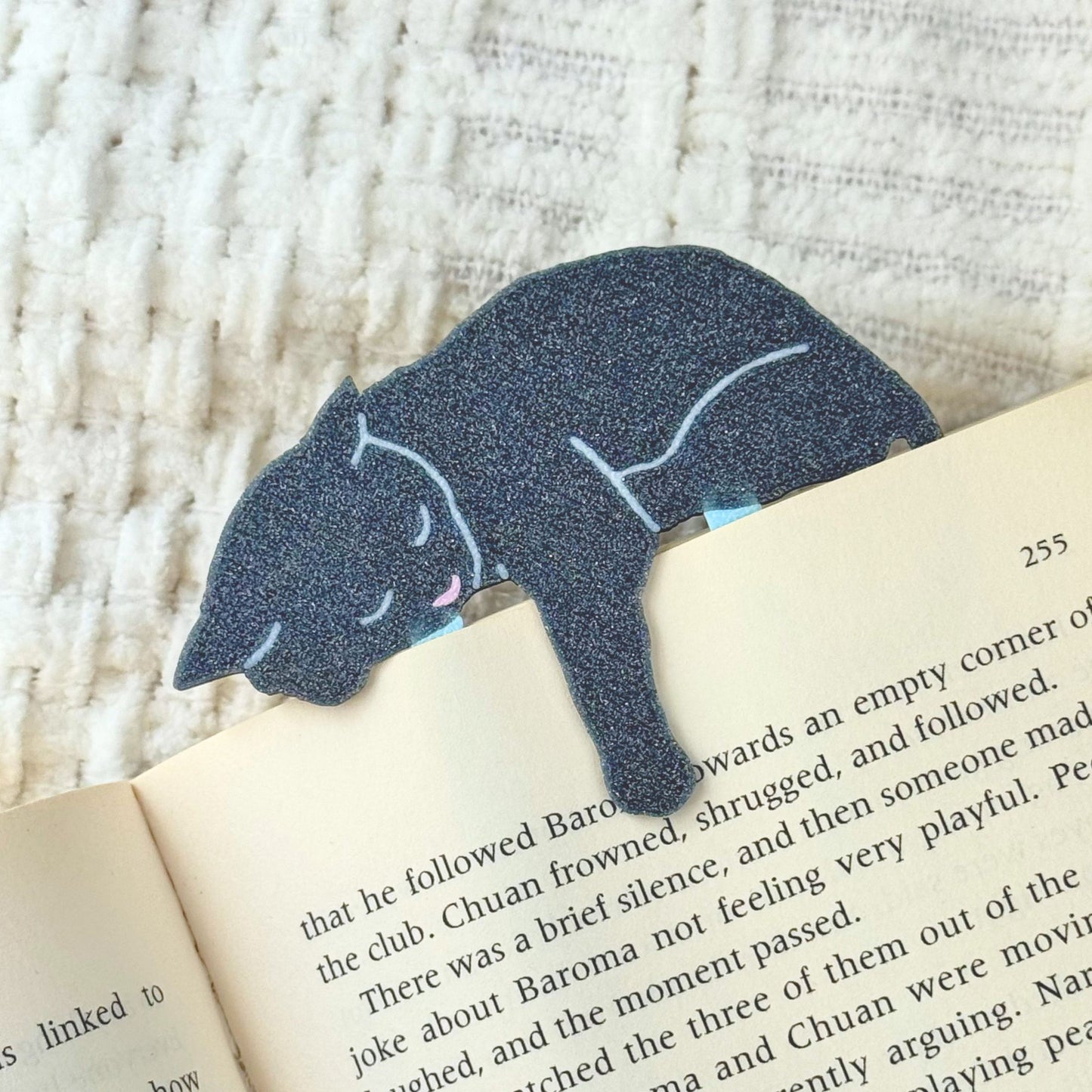 Gray cat-shaped bookmark on an open book