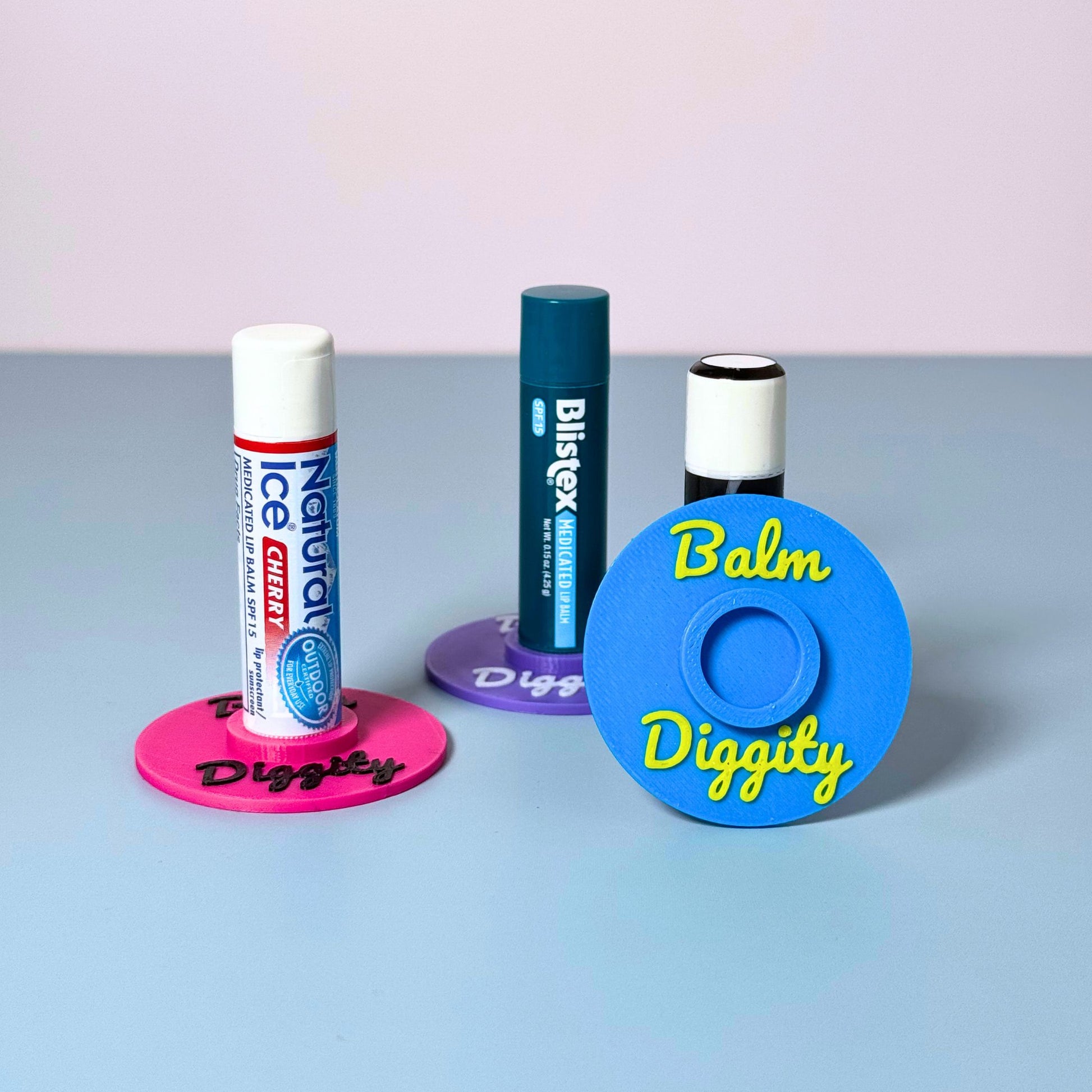 Three vibrant color combinations of the vinyl record lip balm holders including cyan blue, magenta pink, and purple