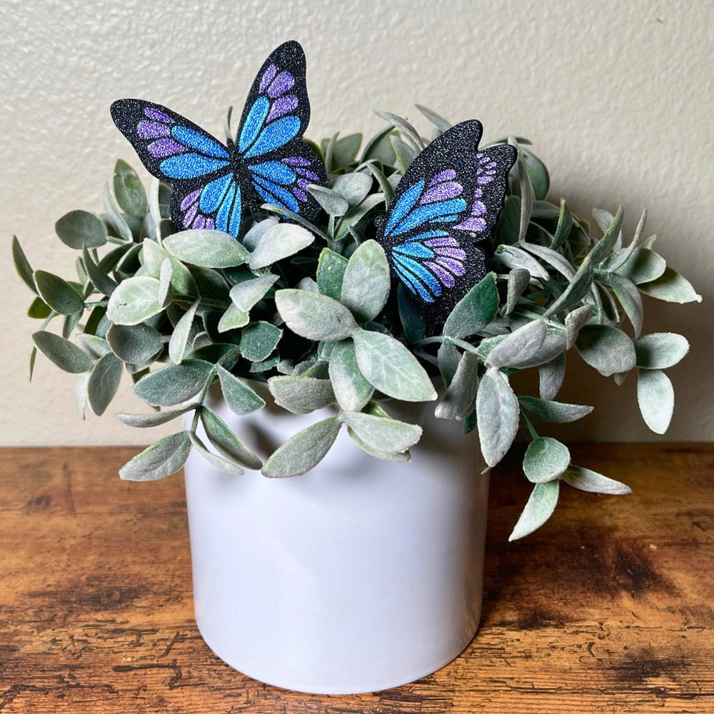 Blue, purple, and black butterfly plant stake set in a houseplant