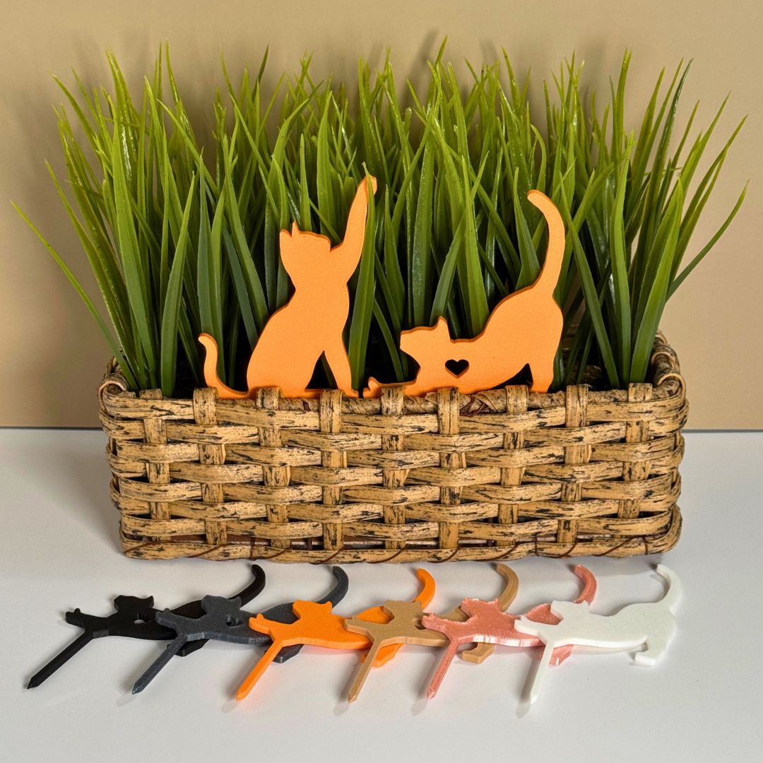 Cute set of orange cat plant stakes stretching and playing inside a houseplant with 6 color options in front of it