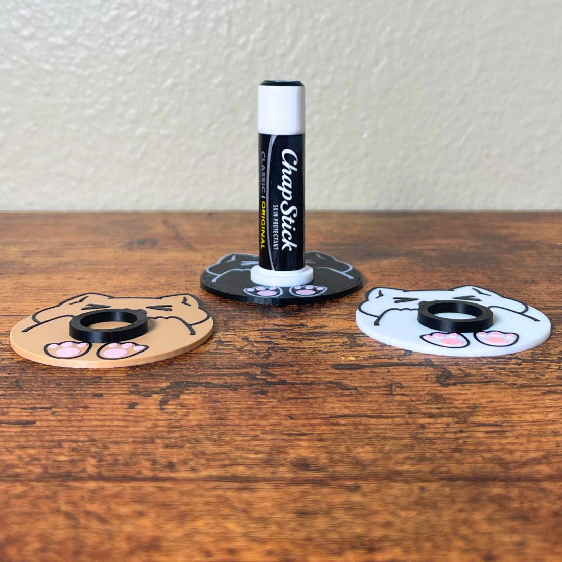 Cute chonk cat lip balm stands in three colors including beige, white, and black
