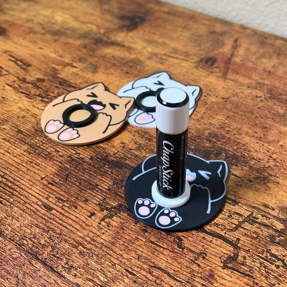 Cute chonk cat lip balm stands in three colors including beige, white, and black