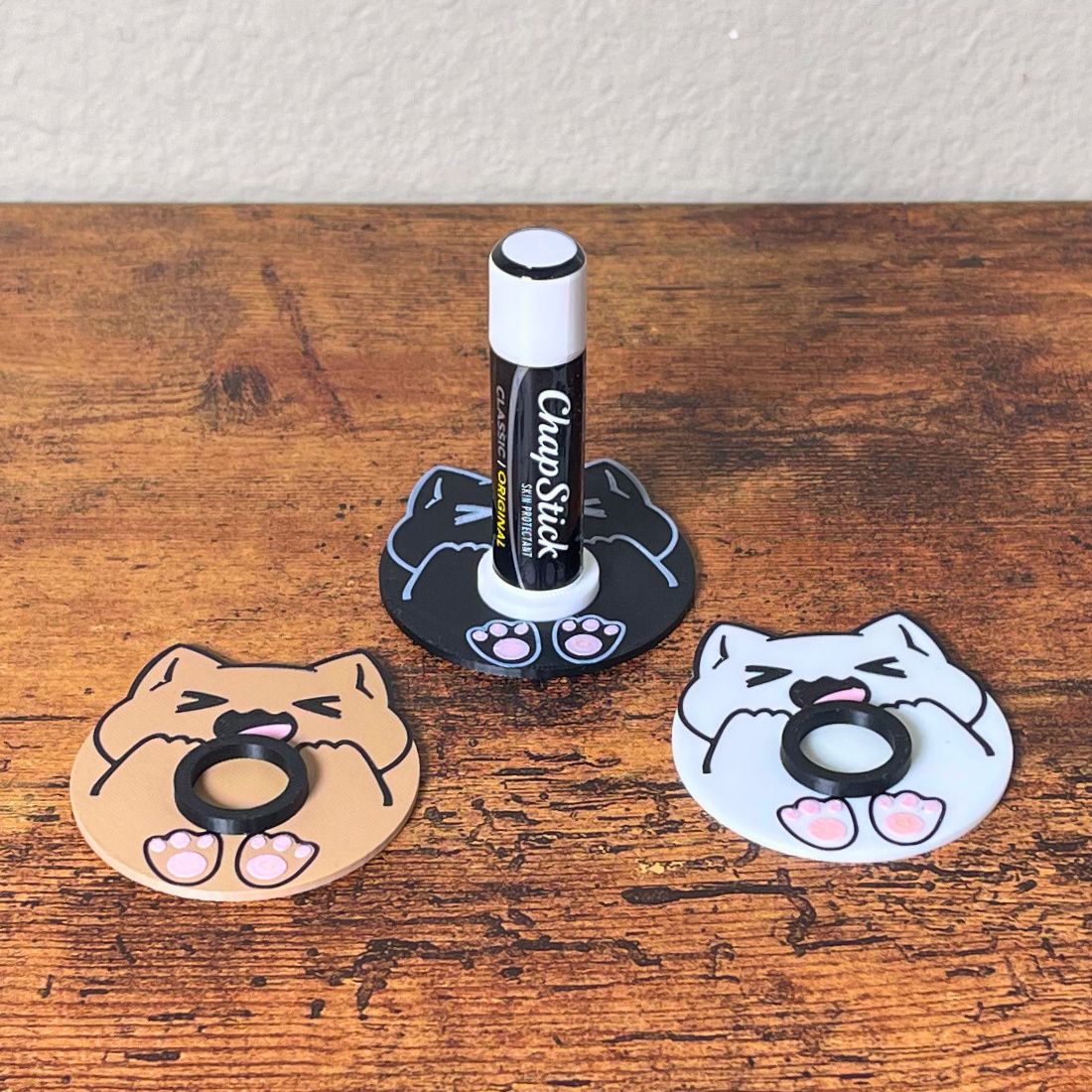 Cute chonk cat lip balm stands in three colors including beige, white, and black