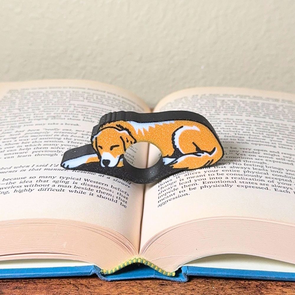 Adorable sleeping gold and white golden retriever dog book page holders shown in a book