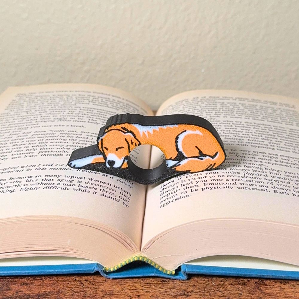 Adorable sleeping orange and white golden retriever dog book page holders shown in a book
