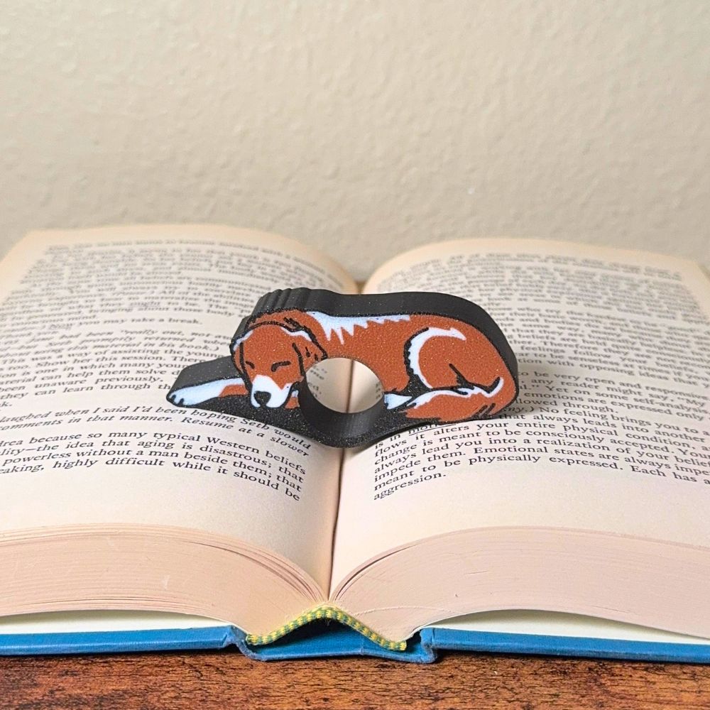 Adorable sleeping brown and white golden retriever dog book page holders shown in a book