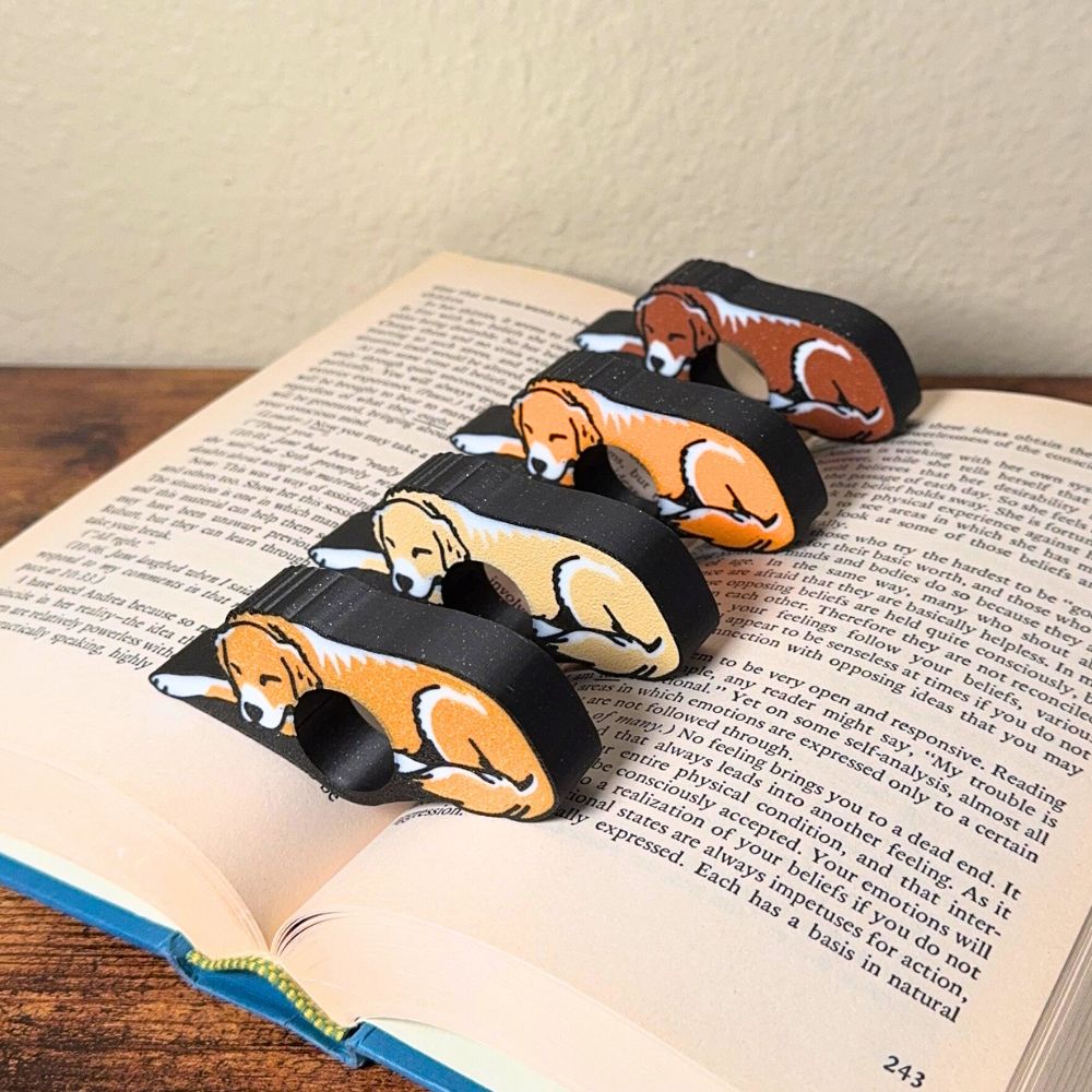 All 4 fur color variations for the sleepy golden retriever dog book page holders shown in a book from the side view
