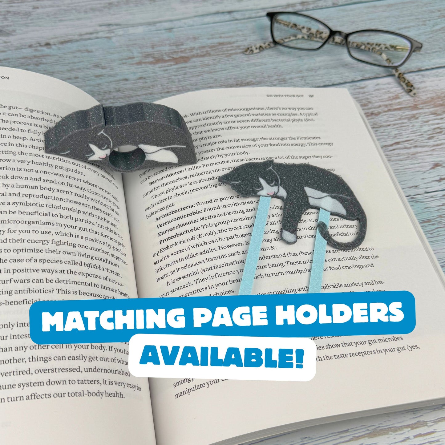 Matching set of gray and white tuxedo cat bookmark and page holder shown in a book