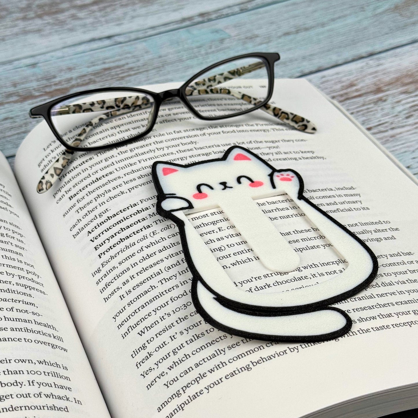 Cute kawaii style cat bookmark in a book with reading glasses