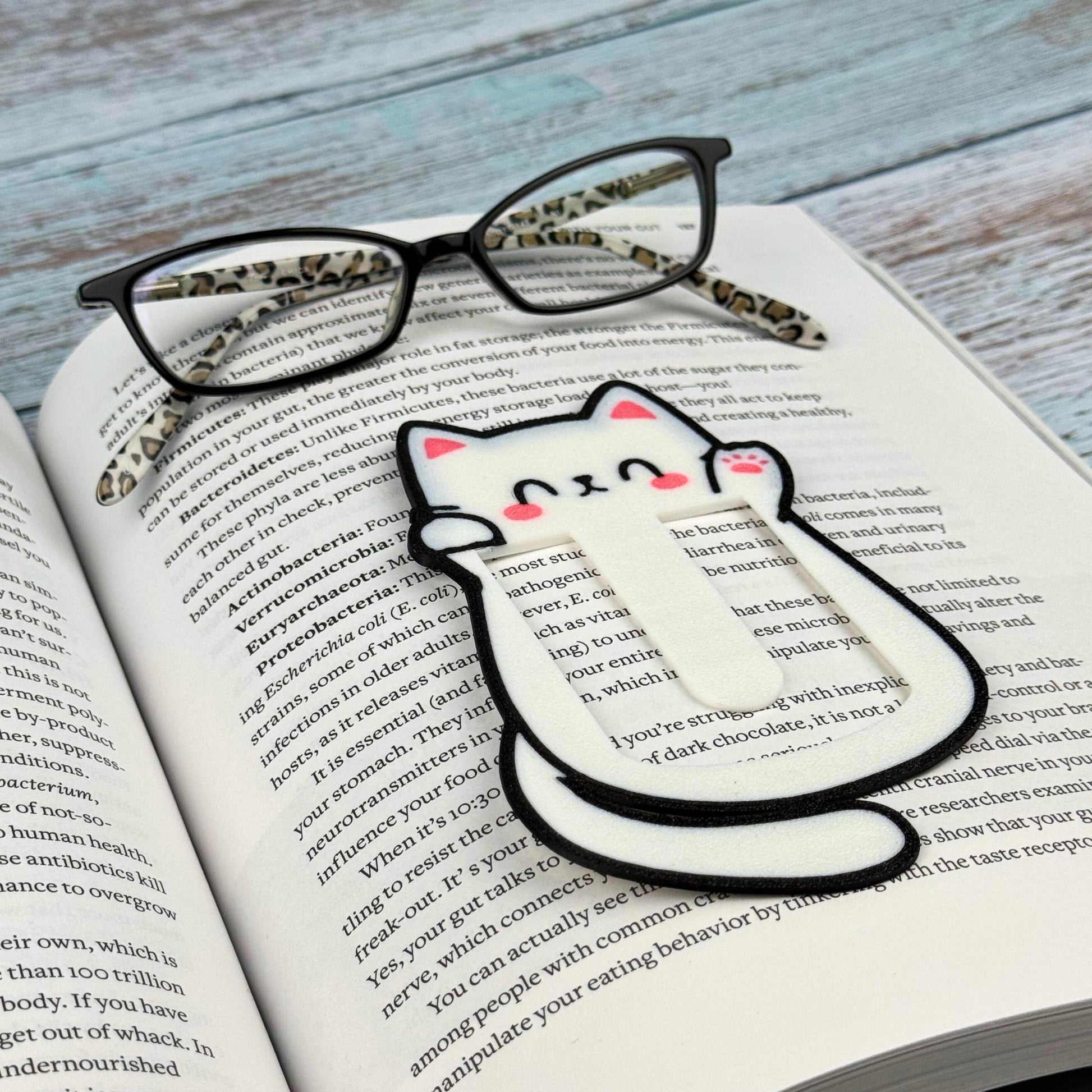 Cute kawaii style cat bookmark in a book with reading glasses
