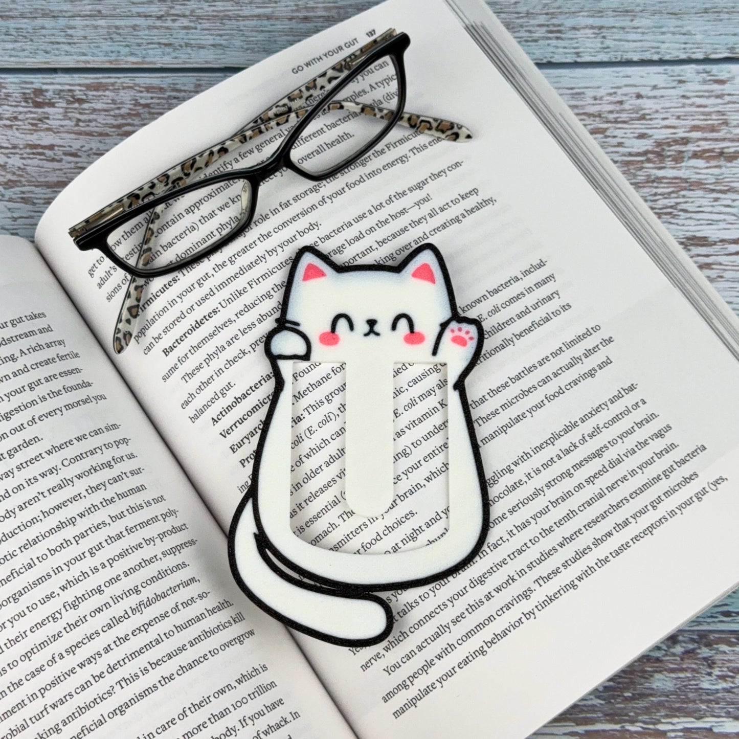 Cute kawaii style cat bookmark in a book with reading glasses
