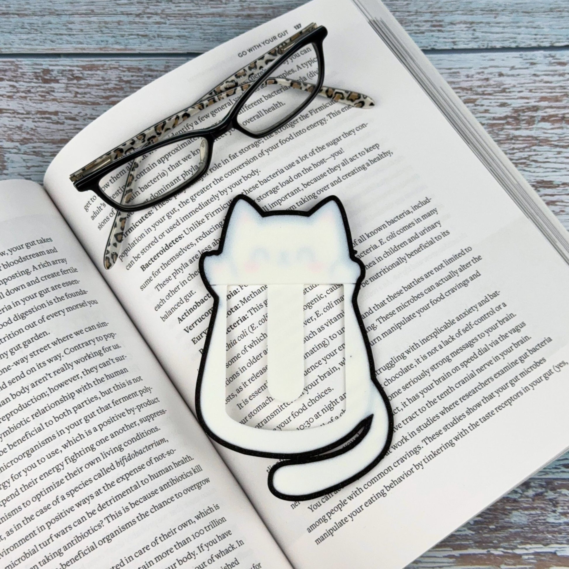 Cute kawaii style cat bookmark in a book with reading glasses