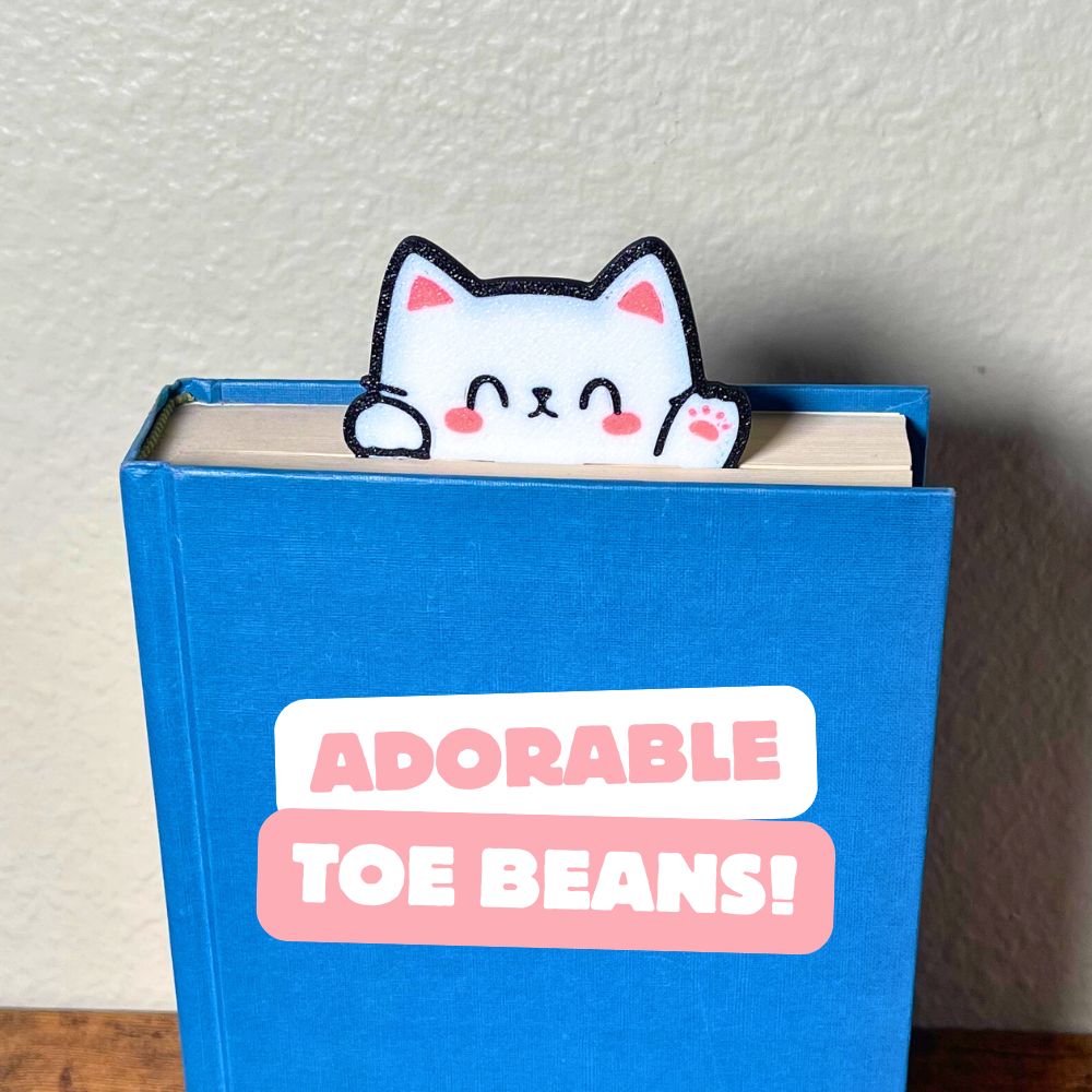 Cute kawaii style cat bookmark waving hello from a blue book showing off its cute pink toe beans