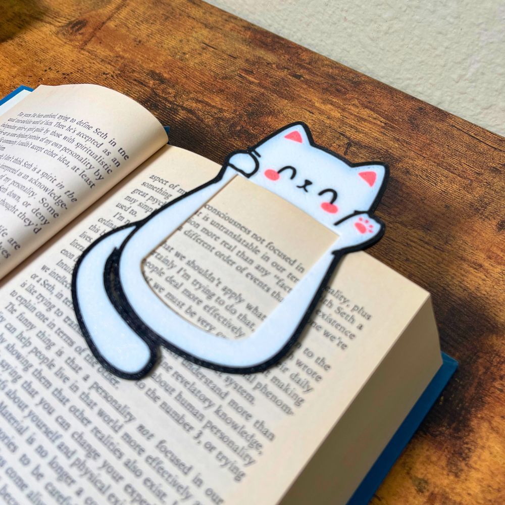 Cute kawaii style cat bookmark waving hello clipped onto the page of a blue book from an angle