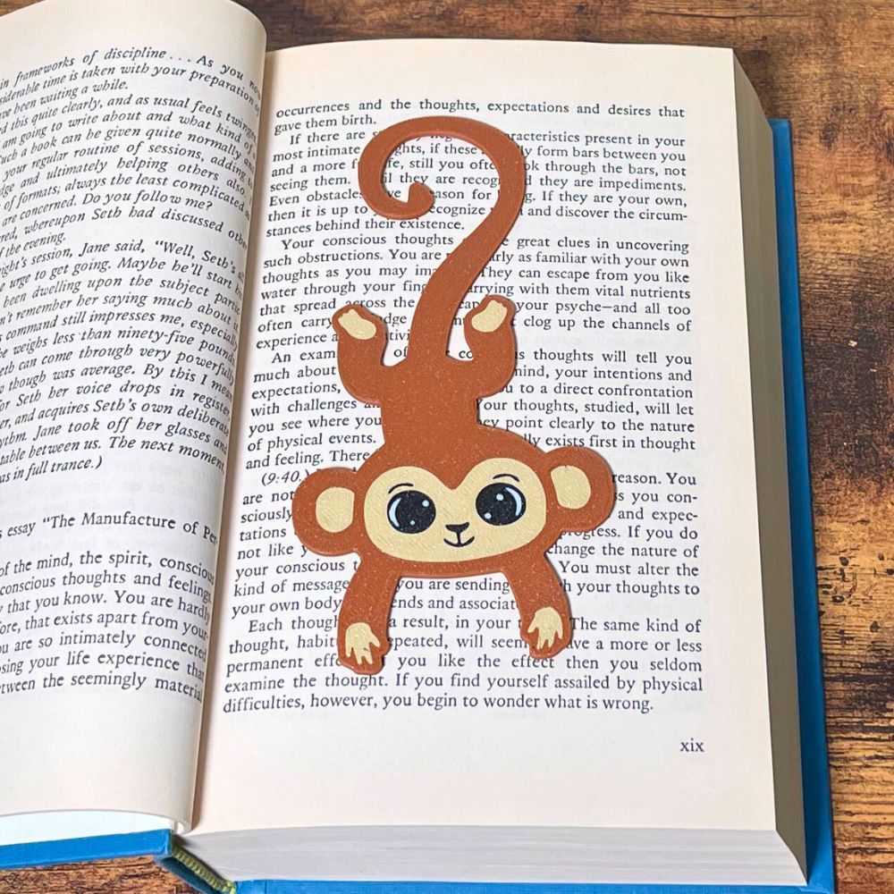 Cute brown monkey bookmark inside of a book