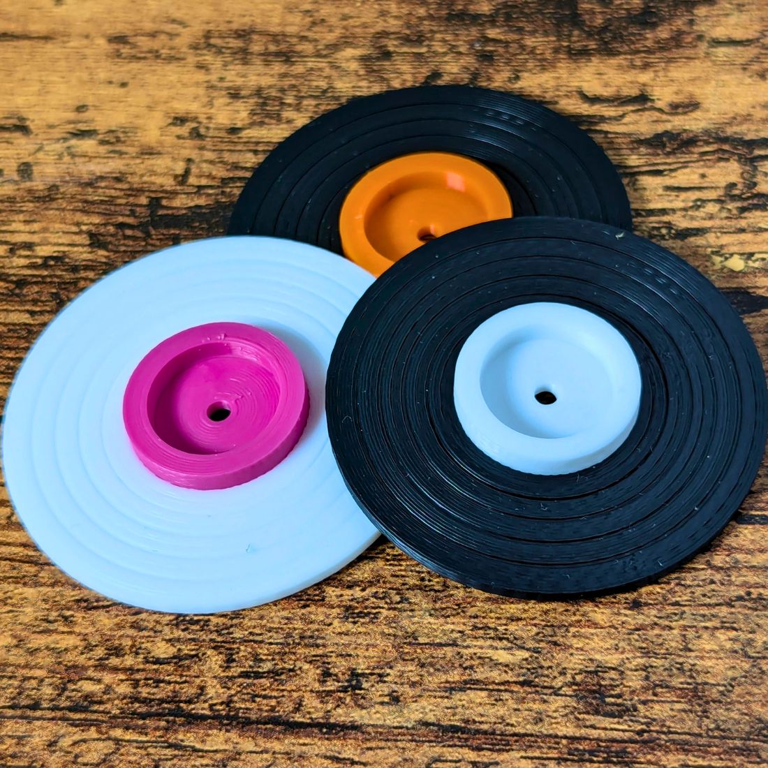 Three color variations of the vinyl record lip balm stands