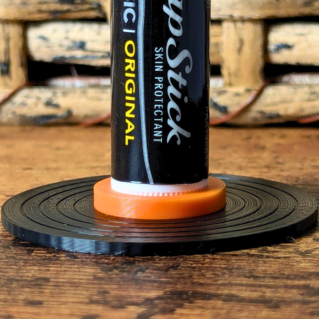 Black and orange vinyl record lip balm stand holding a chapstick up
