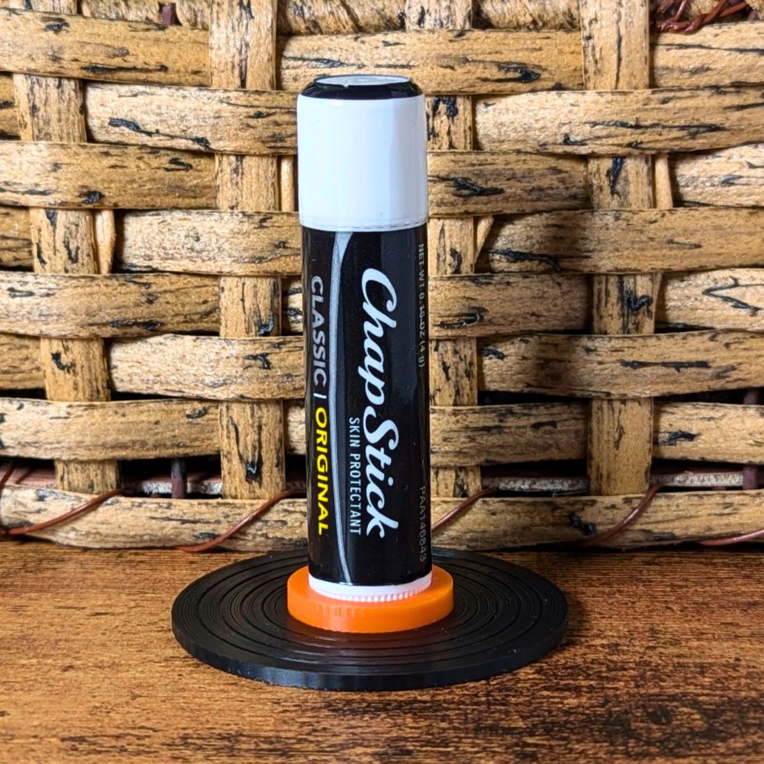Black and orange vinyl record lip balm stand holding a chapstick up
