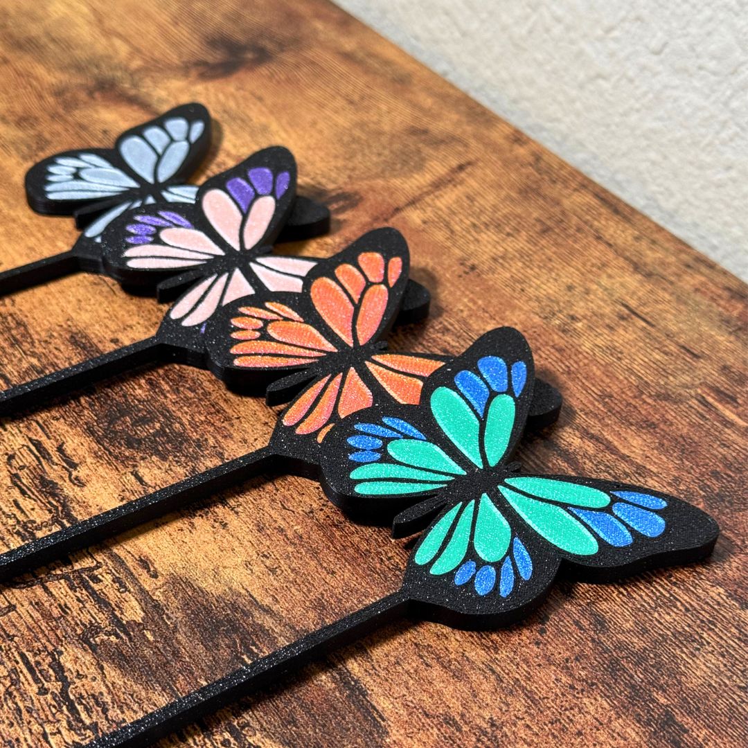 4 color combinations of the butterfly plant stakes laying on a wooden surface taken from an angle