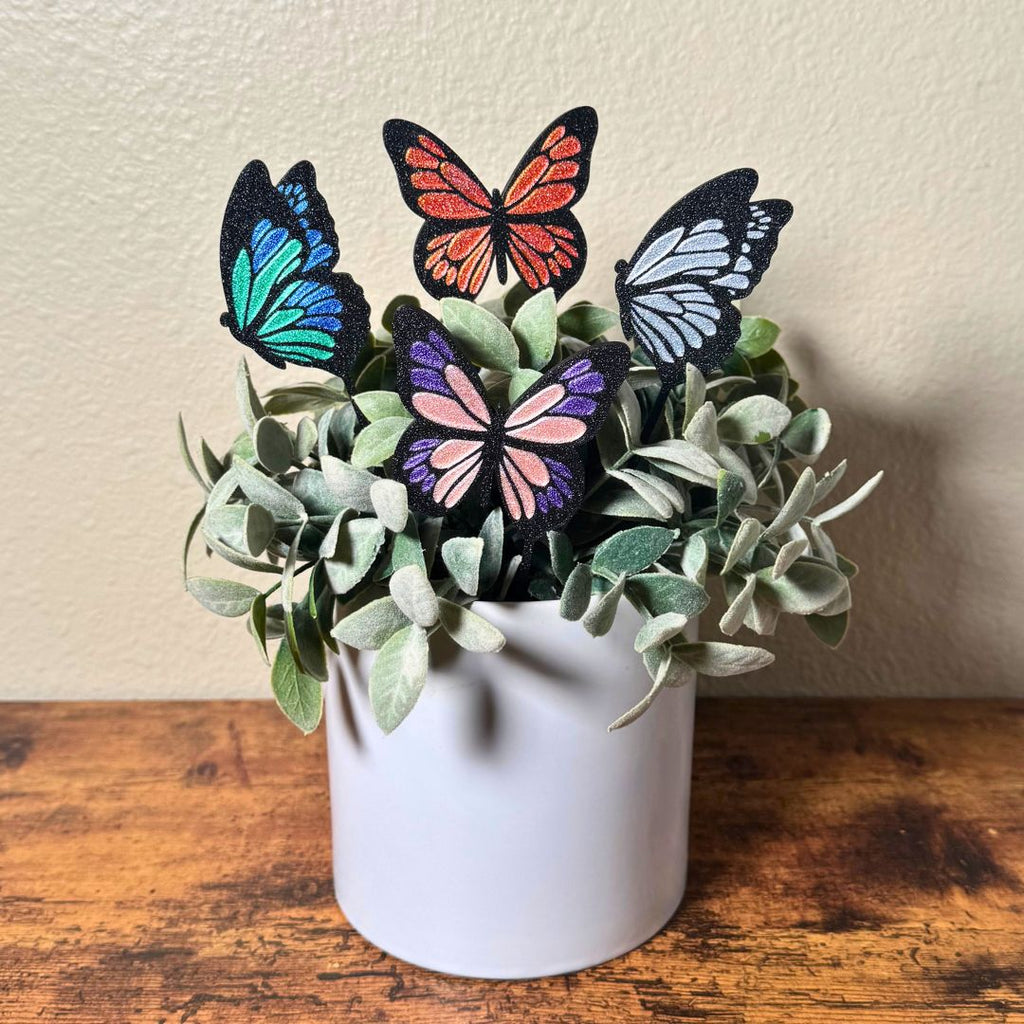 4 color variations of the tall butterfly plant stakes in a potted indoor plant
