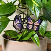 A set of 2 unique and tall butterfly plant stakes with black outlines and sparkling pink and purple highlights