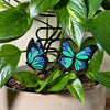 A set of 2 unique and tall butterfly plant stakes with black outlines and sparkling green and blue highlights