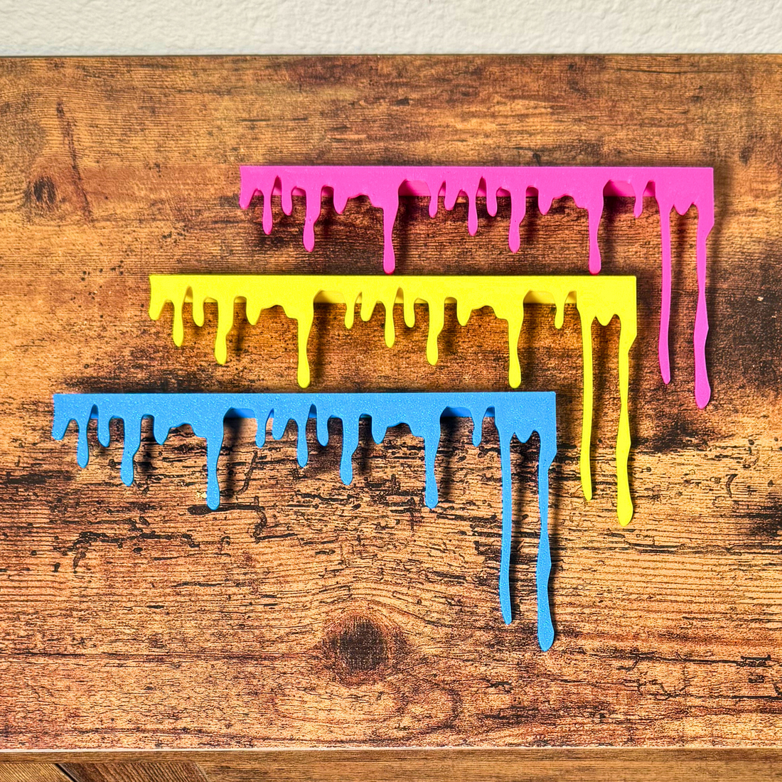 Blue yellow and magenta paint drip door topper hanging on a wooden door frame corner