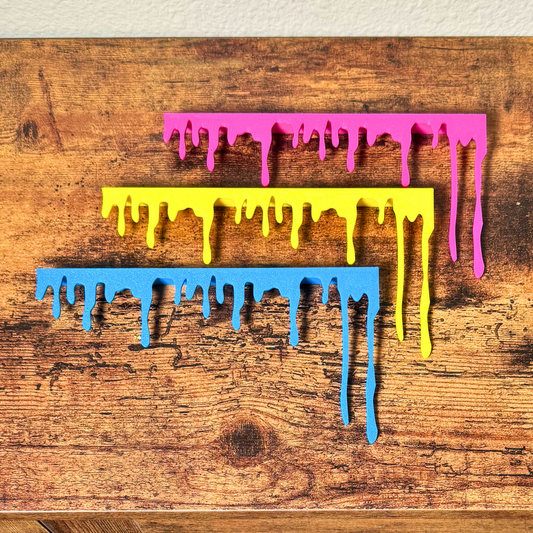 Blue yellow and magenta paint drip door topper hanging on a wooden door frame corner
