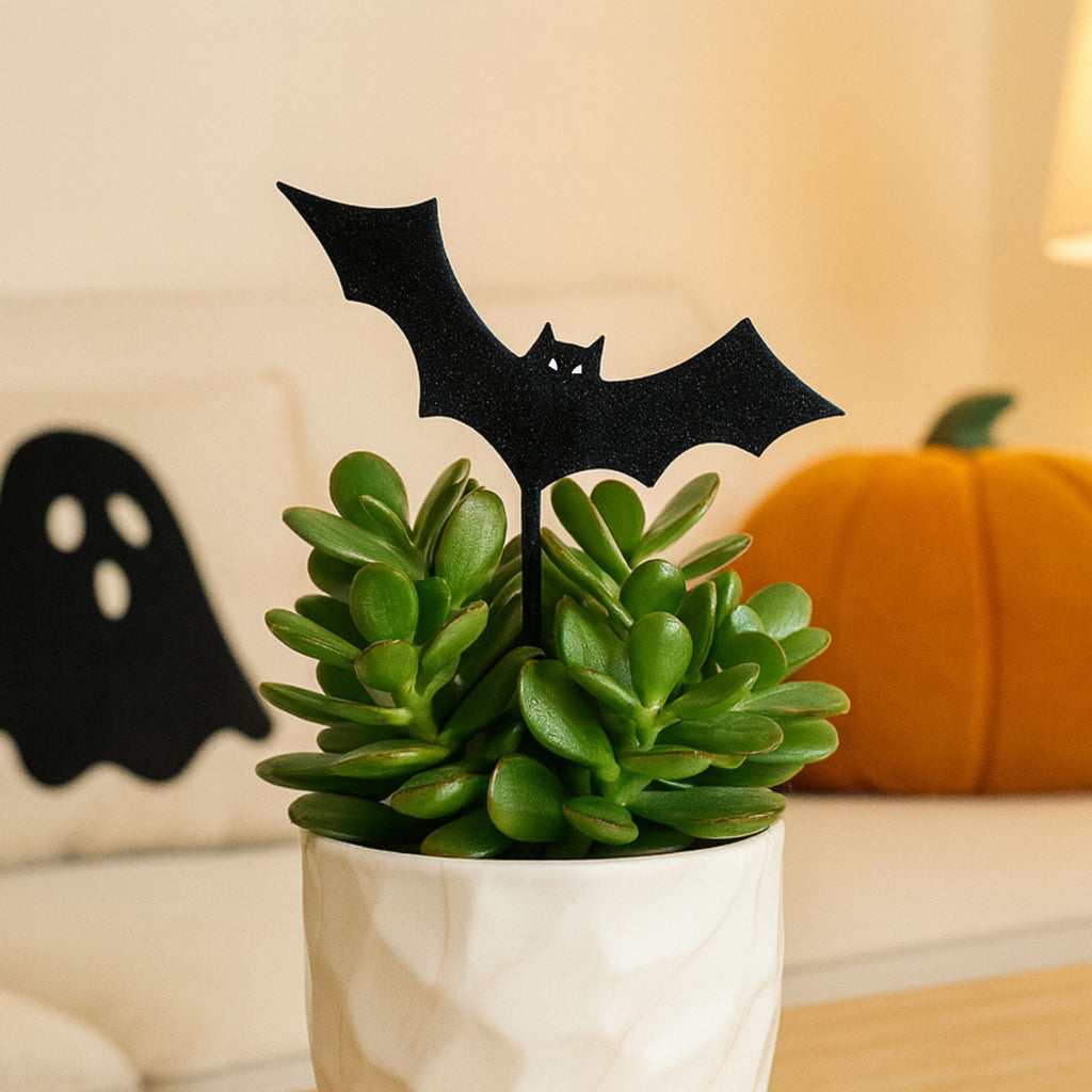 Potted plant with a sparkly flying black bat plant decoration in a cozy Halloween-themed living room
