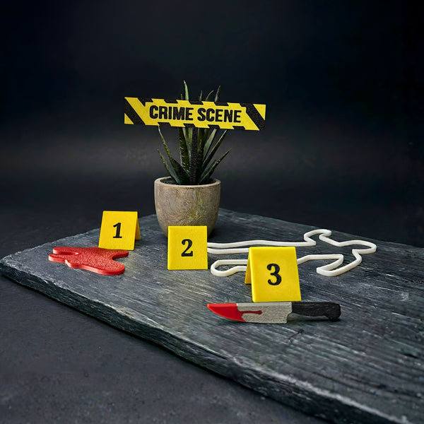 Crime scene setup with a potted plant, 'crime scene' tape plant stake, and numbered markers on a dark surface showing  a blood pile, chalk outline of a body, and a bloody knife.