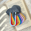 Set of rainbow-colored bookmarks with a gray cat design on an open book.