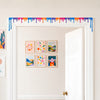 Multicolor liquid drip door topper spanning the full top trim of a white doorway with a gallery wall behind