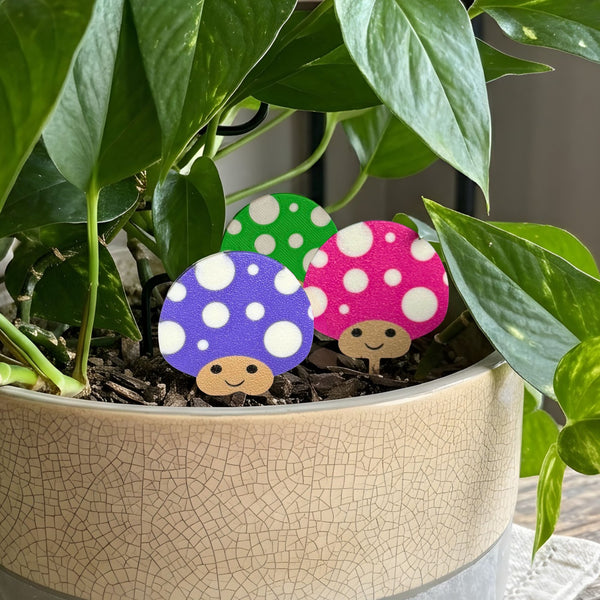 Purple, pink and green polka dot mushroom plant stakes for houseplants tucked in a potted pothos