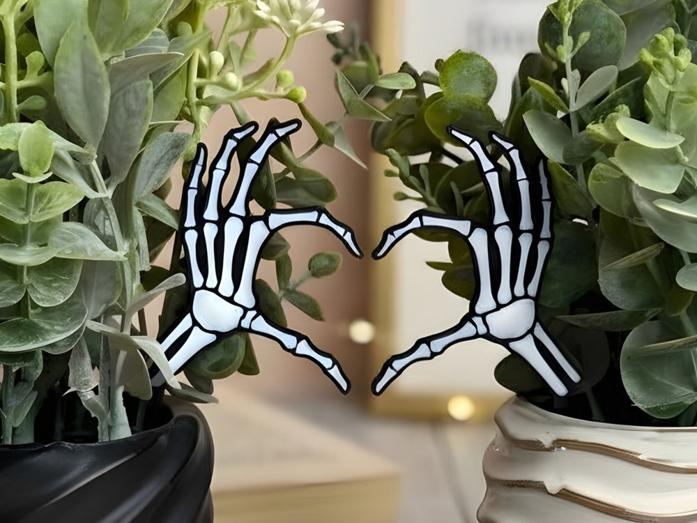 Two skeleton hands plant stakes making a heart shape surrounded by green plants.