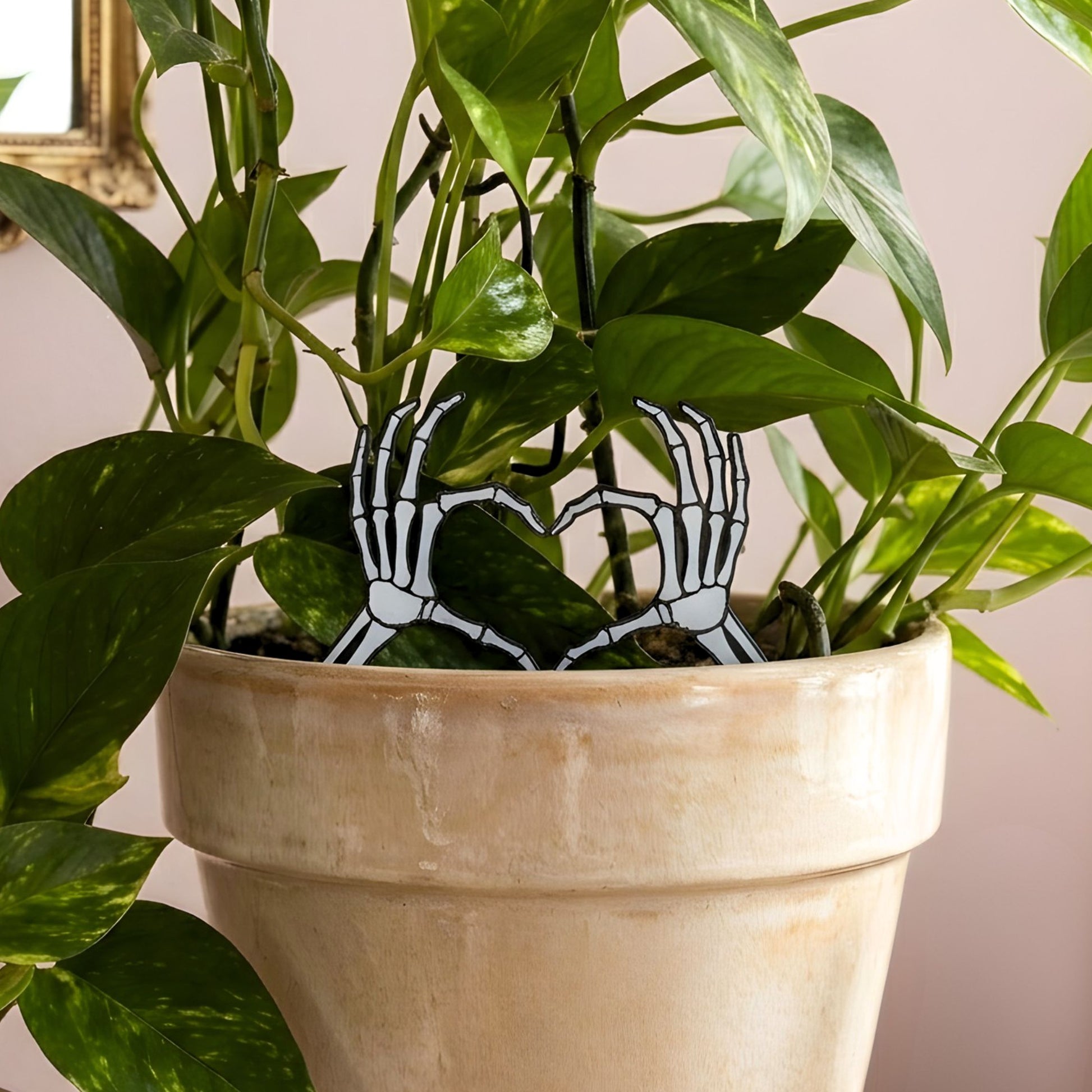 Potted plant with skeleton hand plant stakes inside