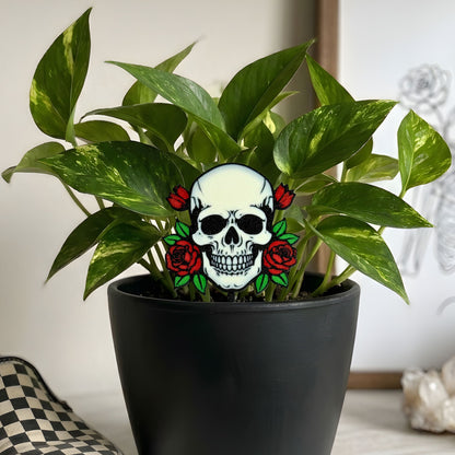 Potted plant with a decorative skull and roses plant stake in a neutral room