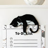 Black tuxedo cat fridge magnet holding a cat-themed to-do list on a refrigerator