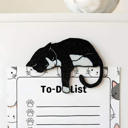 Black tuxedo cat fridge magnet holding a cat-themed to-do list on a refrigerator