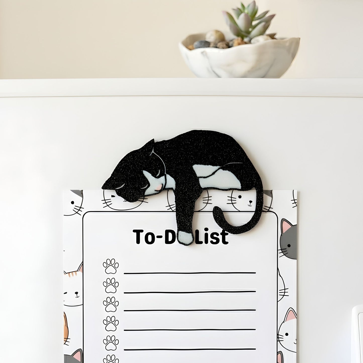 Black tuxedo cat fridge magnet holding a cat-themed to-do list on a refrigerator