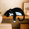 Tuxedo cat shelf pet draped over a wooden shelf edge, black and white cat decor with candle and frame