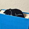 Black cat bookmark shown in a closed book taking a nap on top