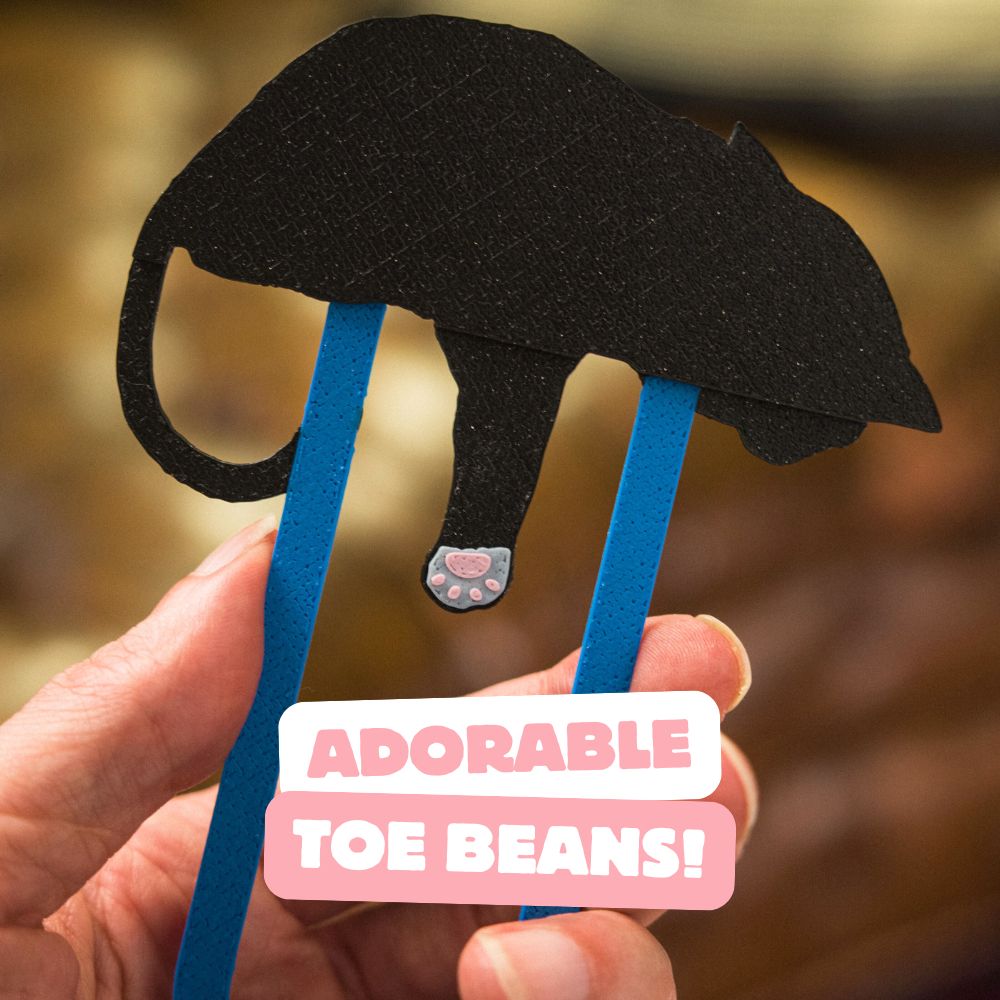 The back of a tuxedo cat bookmark showing the adorable pink toe beans on the back of its paw
