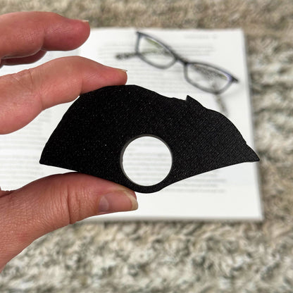 Back of the product showing an all black color held by a hand with a blurred background