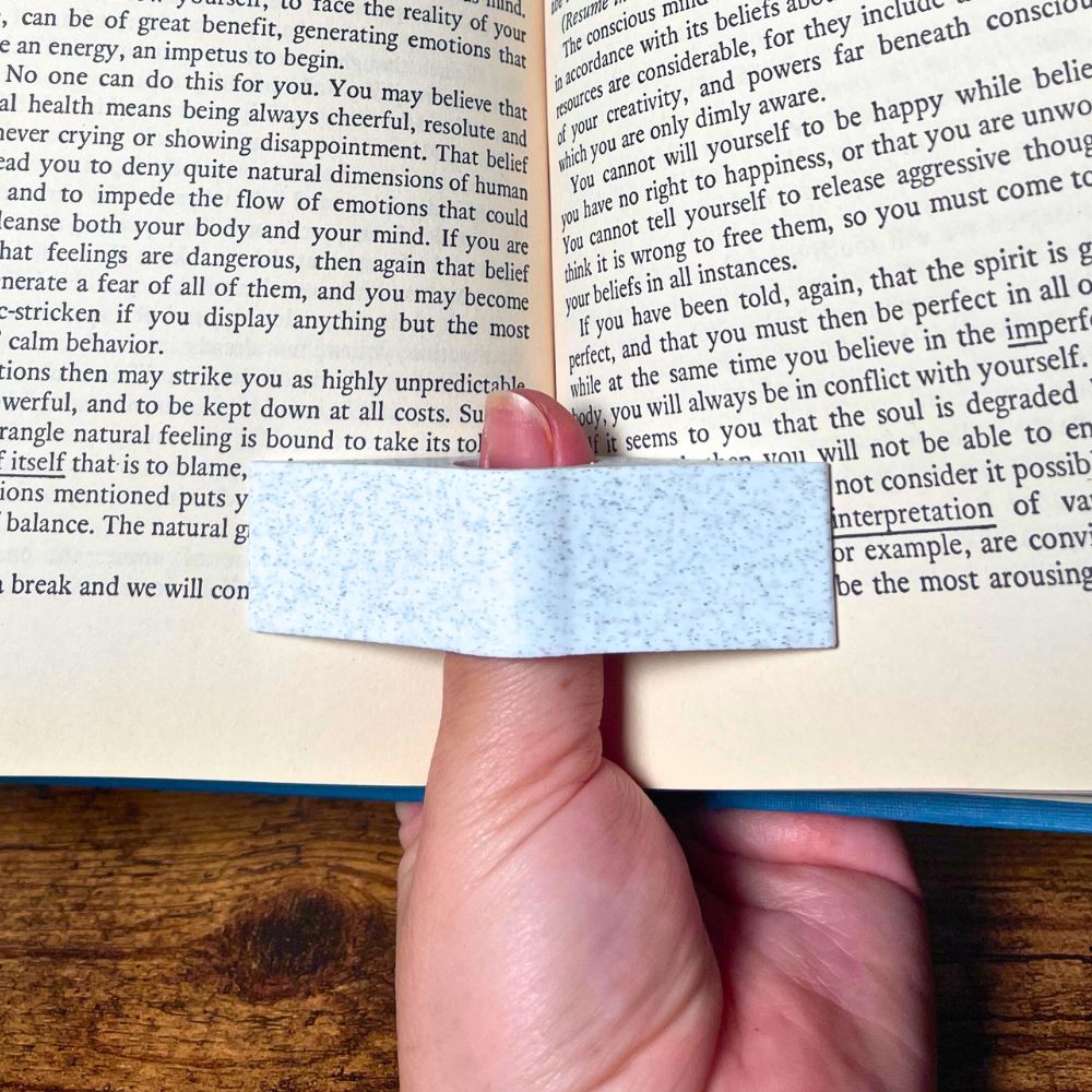 A marble book page holder holding a book open showing off its functionality