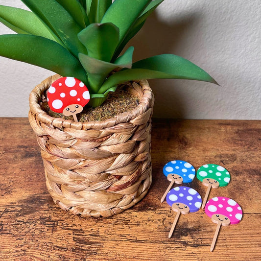 Cute mushroom plant stakes shown in 5 color variations with adorable smiling faces
