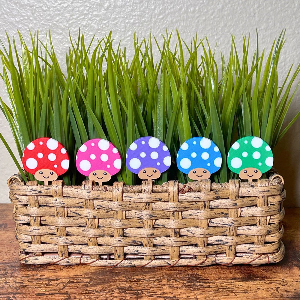 Cute mushroom plant stakes shown in 5 color variations with adorable smiling faces