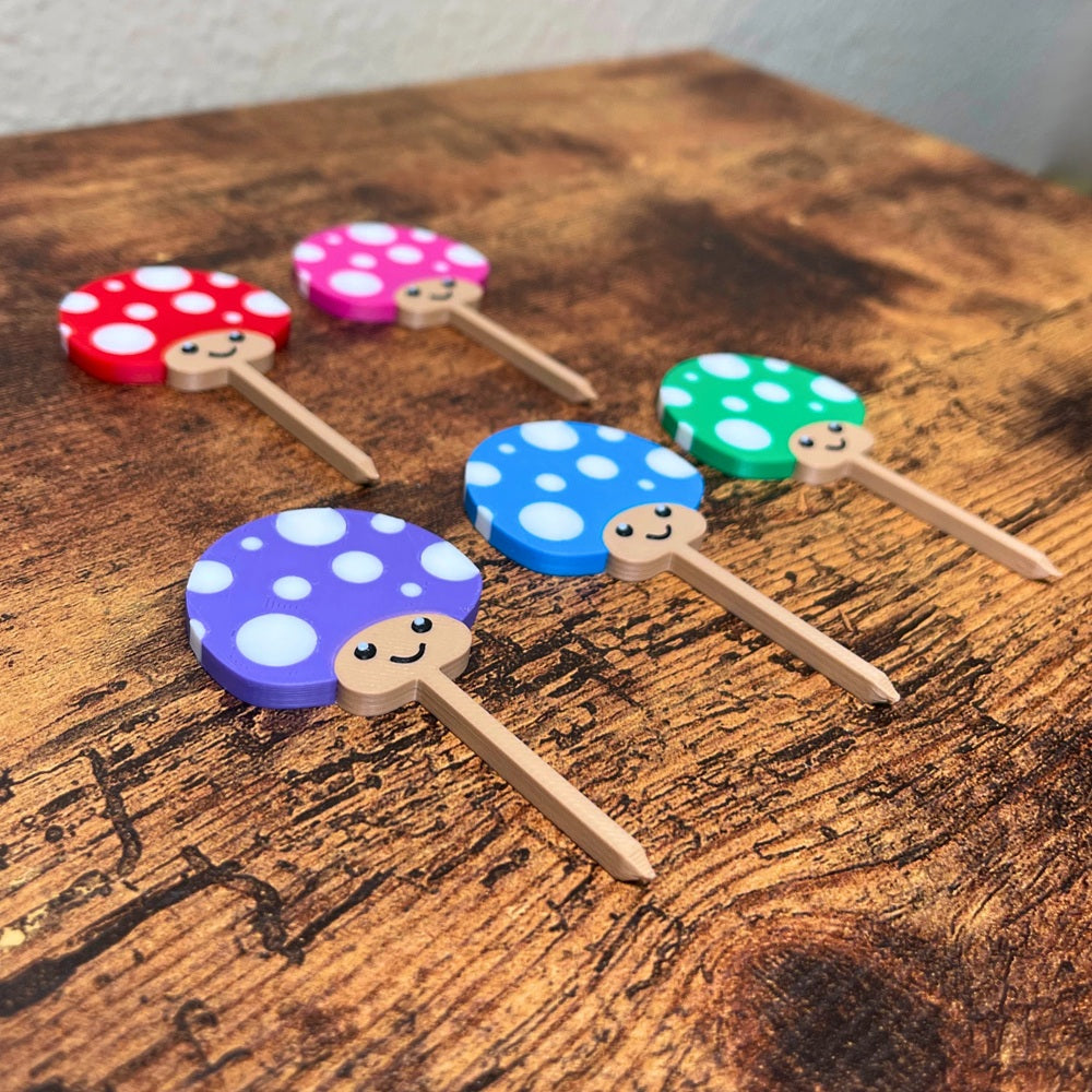 Cute mushroom plant stakes shown in 5 color variations with adorable smiling faces from an angle