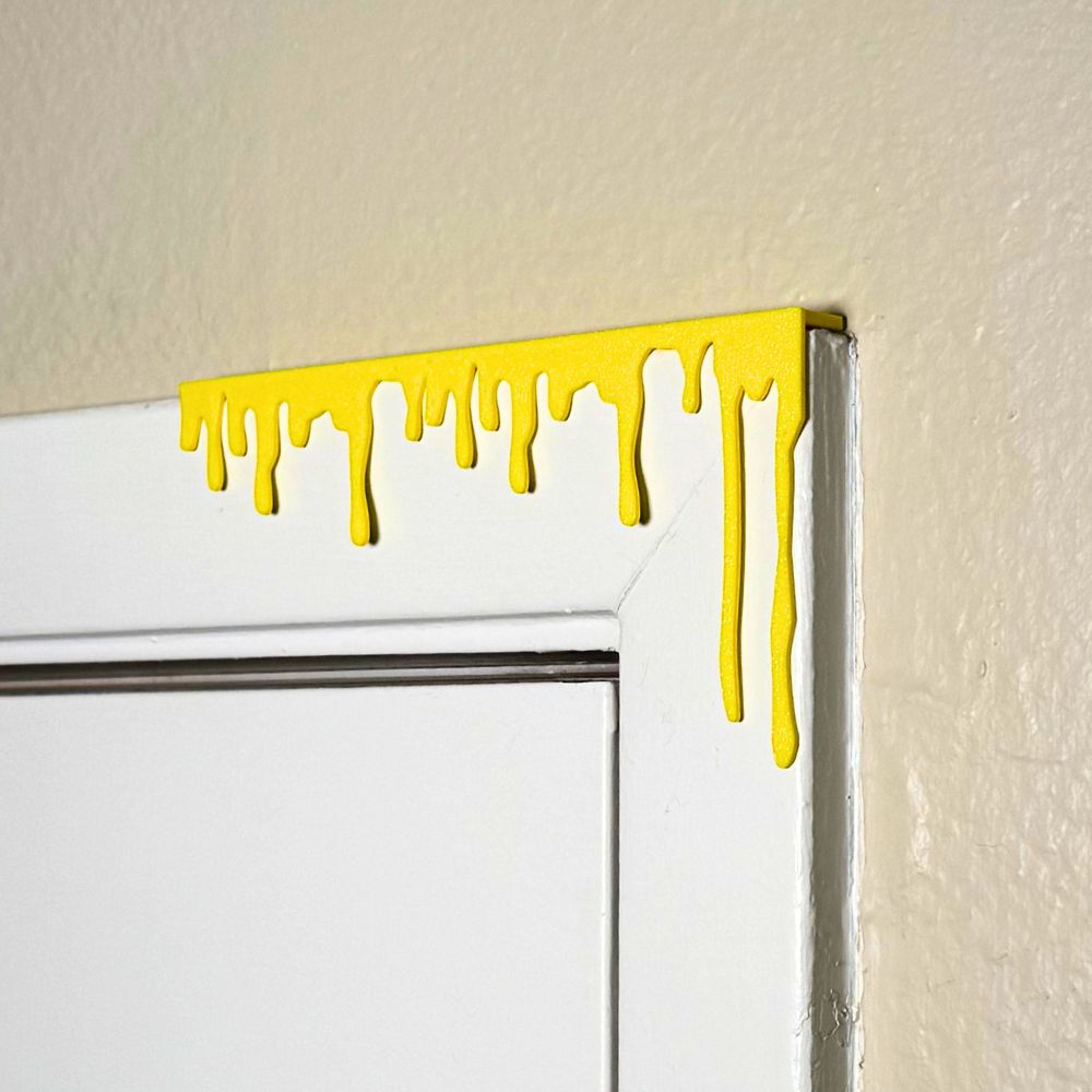 Yellow paint dripping door corner wall art hanging from the right side of the door