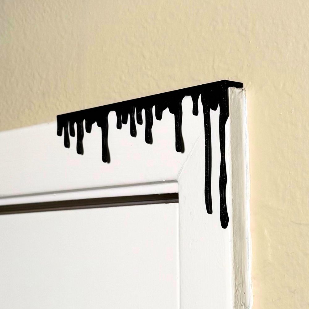 Black paint dripping door corner wall art hanging from the right side of the door