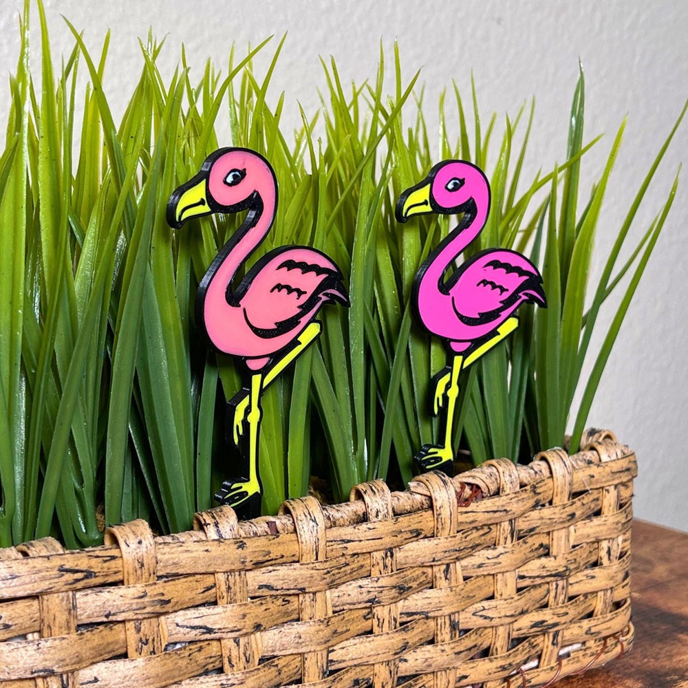 Fun flamingo plant stakes shown in a houseplant from an angle